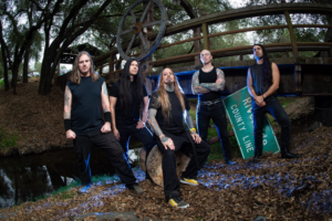 DevilDriver band members posing outdoors near a wooden bridge