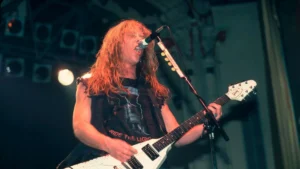 Young James Hetfield singing and playing white guitar live on stage