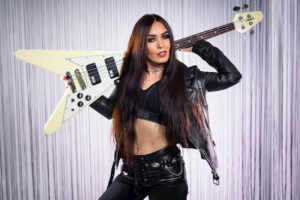 Musician with V‑shaped bass guitar in leather outfit