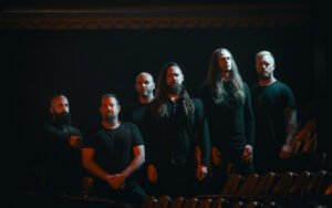 Six‑member band posing in dark theater